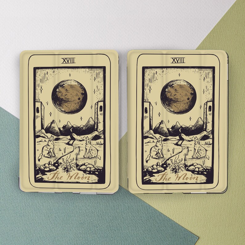 K&ouml;nnte beinhalten: Zwei Tarotkarten mit beigefarbenem Hintergrund. Die Karten sind beide die XVIII Die Mondkarte. Die Karten zeigen eine Schwarzwei&szlig;illustration eines Mondes, zweier W&ouml;lfe und einer Krabbe. Die Karten haben einen beigefarbenen Hintergrund mit schwarzem Text.