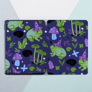 Puede incluir: Una rana verde y morada con un sombrero de mago morado y blanco sobre un fondo azul oscuro con hojas verdes, cristales morados y setas blancas. La rana está rodeada de un patrón de los mismos elementos.