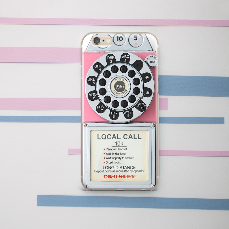 May include: A pink and silver rotary phone case for a smartphone. The case features a vintage rotary phone design with a dial, buttons, and a display that reads "LOCAL CALL 10&cent;" and "CRO-S-LEY".