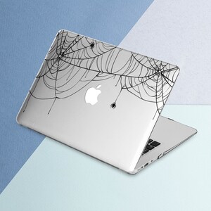 May include: A silver laptop with a black spiderweb design on the lid. The design features several small spiders.