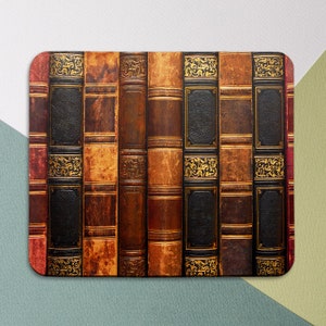 May include: Close-up of a row of antique books with leather covers and gold detailing. The books are arranged vertically and have a worn, aged appearance.