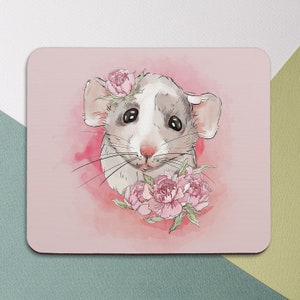 May include: A white and gray mouse with pink flowers on its head and around its neck. The mouse is looking at the viewer with a sweet expression. The background is a soft pink watercolor wash.