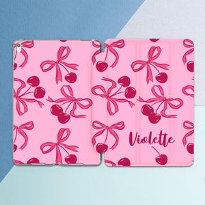 May include: Pink iPad case with a pattern of pink bows and red cherries. The case has the name "Violette" printed on the back.