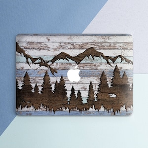 May include: A laptop skin with a wood grain background and a silhouette of mountains and trees. The skin has a blue and white color scheme.