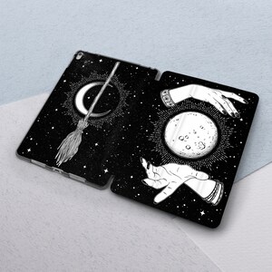 May include: Black and white illustration of a crescent moon, stars, and a broom with a hand holding a full moon. The design is on a black background.