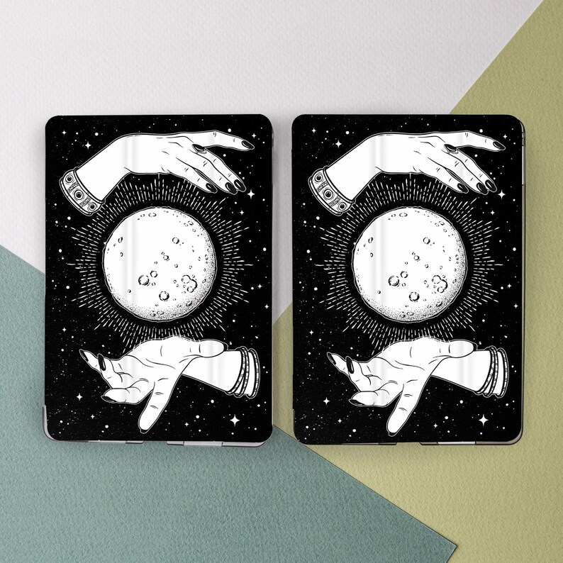 May include: Two black phone cases with a white design of a hand holding a moon with a starry background.