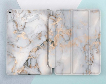 May include: A white and gold marble iPad case with a folding cover. The case is made of a hard plastic material and has a smooth finish.