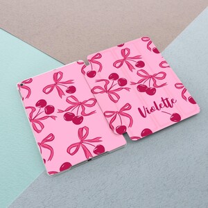 May include: Pink iPad case with a cherry and bow pattern. The case has the name "Violette" printed on the back.