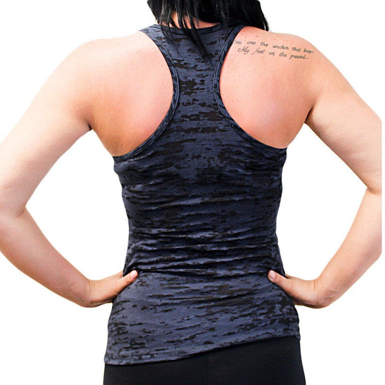 Op de afbeelding: Een donkerblauw racerback tanktop met een vervaagde, verweerde look. Het tanktop heeft een ronde hals en een racerback-ontwerp. De achterkant van het tanktop heeft een citaat dat luidt: "Jij bent het anker dat alleen voeten op de grond houdt."