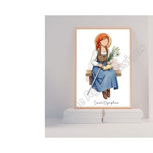May include: A printable art print featuring a watercolour illustration of Saint Dympna, a Catholic saint, sitting on a bench with a book and flowers. The print has a white background and the text "Saint Dympna" at the bottom.