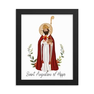 Op de afbeelding: Een ingelijste print van een religieuze illustratie die de heilige Augustinus van Hippo voorstelt. De afbeelding toont een man in een rode en witte robe die een boek en een staf vasthoudt. De achtergrond is wit met bloemmotieven.