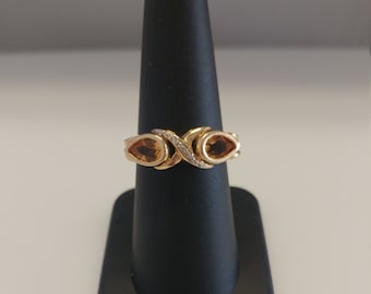 May include: A gold ring with two pear-shaped topaz gemstones and a diamond accent.