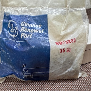 以下が含まれることがあります： GEのロゴとGenuine Renewal Partと記された透明なビニール袋に入った交換部品。赤色でWB23X33および35 91と印字されています。その他、GE、RCA、Hotpointの文字も記載されています。袋は密封されており、しわが寄っています。