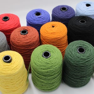 May include: A collection of colorful yarn cones in various shades, including red, blue, orange, green, and black. Each cone has a black center and is tightly wound. The yarn is likely for knitting or crocheting projects.