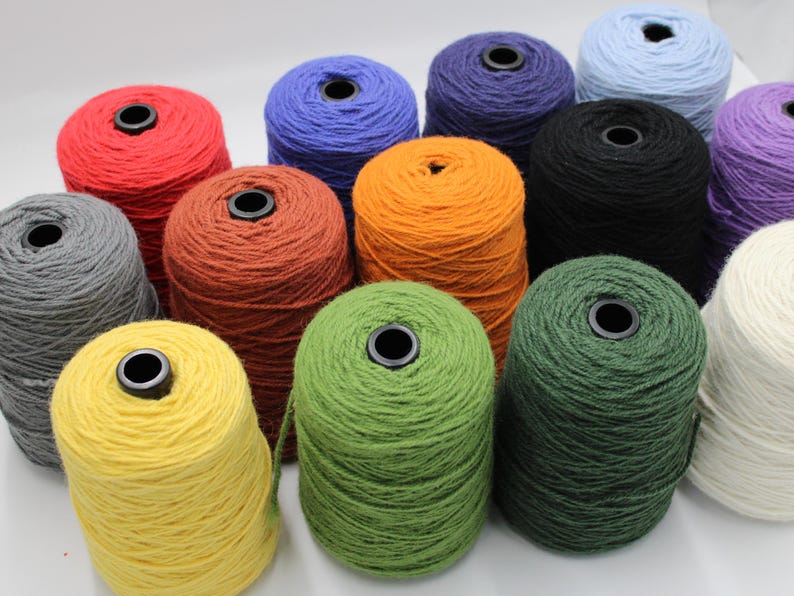 May include: A collection of colorful yarn cones in various shades, including red, blue, orange, green, and black. Each cone has a black center and is tightly wound. The yarn is likely for knitting or crocheting projects.