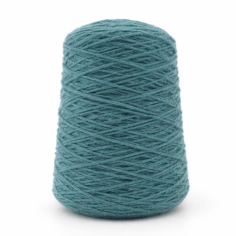 May include: A teal-colored yarn cone, tightly wound with visible texture. The yarn is a solid, muted teal, and the cone shape tapers from a wider base to a narrower top. Ideal for knitting and crochet projects.