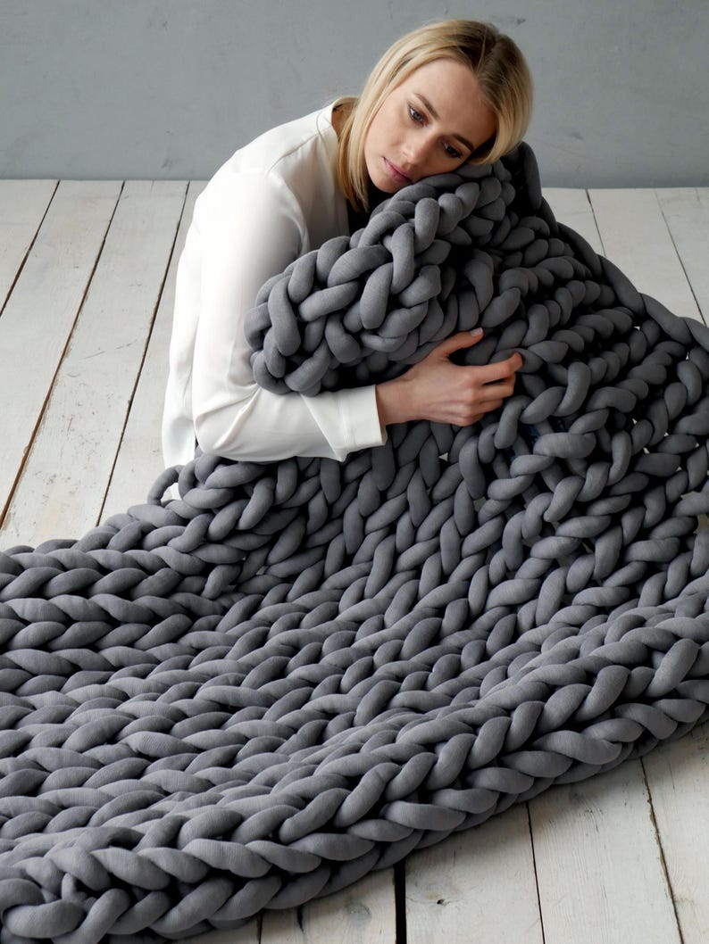 Girl is holding a weighted blanket. Handmade cotton weighted chunky knit blanket – perfect for PTSD, fibromyalgia, anxiety, ADHD, and sensory needs. It is a cotton weighted blanket - does not have glass beads. It is a handmade knit from cotton tube yarn, blanket is made by the weight that you need, from the cotton yarn amount that you need.