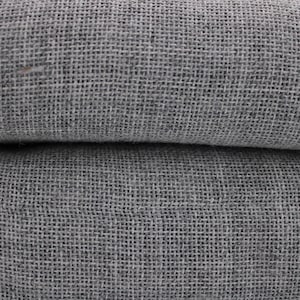 May include: Close-up of a folded, gray linen fabric. The fabric has a coarse, woven texture, with visible threads creating a grid-like pattern. The color is a muted gray, with subtle variations in tone. The fabric appears to be soft and pliable.