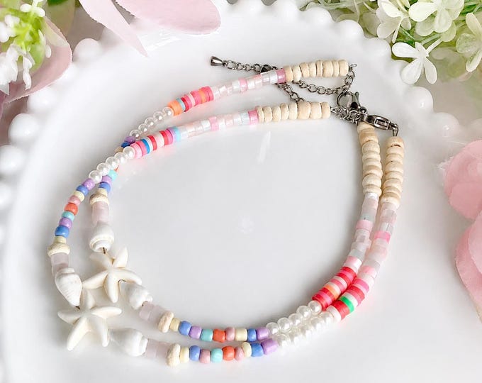 Bracelet avec mélange délicat de perles colorées, perles nacrées et perles naturelles, rehaussé d’un motif étoile de mer et coquillage