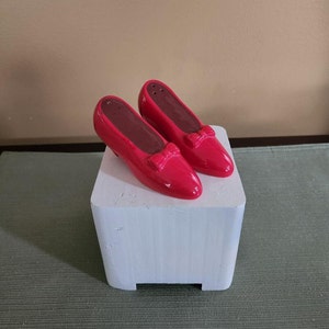 May include: A pair of red ceramic salt and pepper shakers shaped like high-heeled shoes with bows.