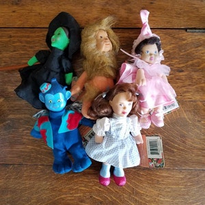 May include: A set of five Wizard of Oz plush toys. The characters include Dorothy, the Wicked Witch of the West, the Cowardly Lion, the Tin Man, and the Scarecrow. The toys are all in good condition and have a vintage look.
