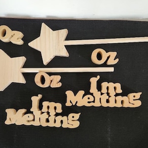 May include: Wooden craft supplies with the words "Oz" and "I'm Melting" in a whimsical font. There are two wooden stars with sticks attached to them.