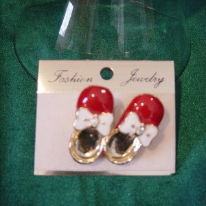 May include: Red and white shoe-shaped earrings with a bow and a rhinestone on each shoe. The earrings are on a white card with the words "Fashion Jewelry" printed on it.