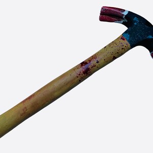 May include: A yellow wooden handled hammer with red and black paint splattered on it. The hammer head is black with red paint on the claw and the hammer face.