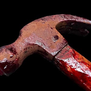 Pu&ograve; includere: Un martello arrugginito con un manico di legno ricoperto di vernice rossa, che ricorda il sangue.