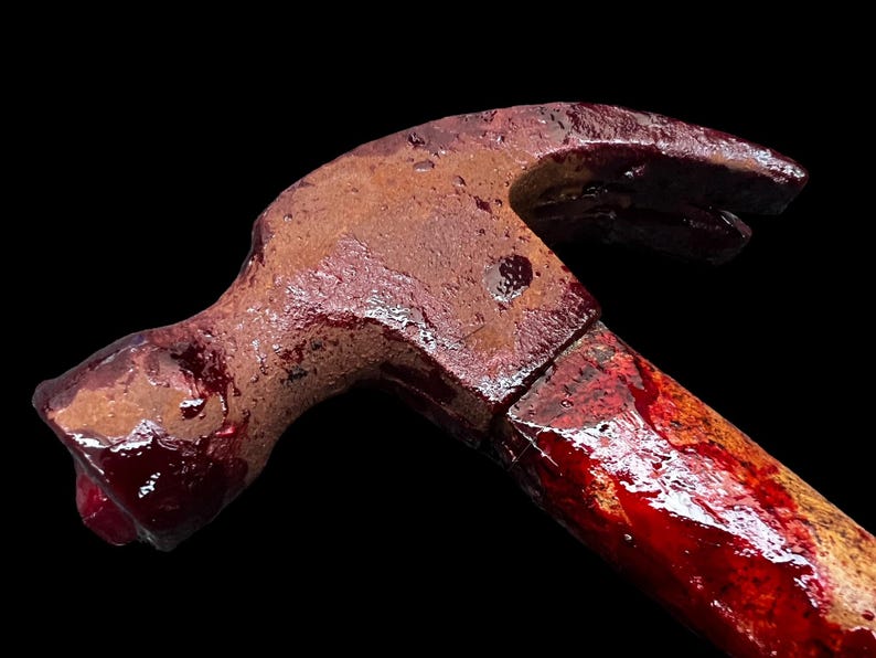 Pu&ograve; includere: Un martello arrugginito con un manico di legno ricoperto di vernice rossa, che ricorda il sangue.