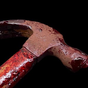 Pu&ograve; includere: Un martello rosso con un manico di legno ricoperto di sangue. Il martello &egrave; uno strumento comune utilizzato per la costruzione e la demolizione.