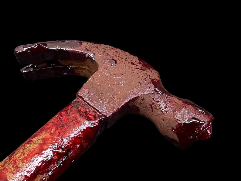 Pu&ograve; includere: Un martello rosso con un manico di legno ricoperto di sangue. Il martello &egrave; uno strumento comune utilizzato per la costruzione e la demolizione.