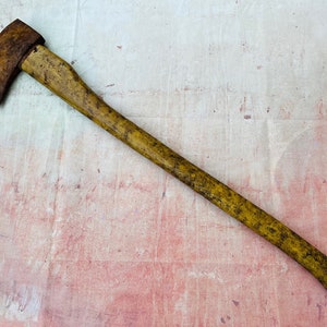 K&ouml;nnte beinhalten: Eine antike Axt mit einem Holzstiel. Die Axtkopf ist rostig und der Stiel ist vom Alter vergilbt.