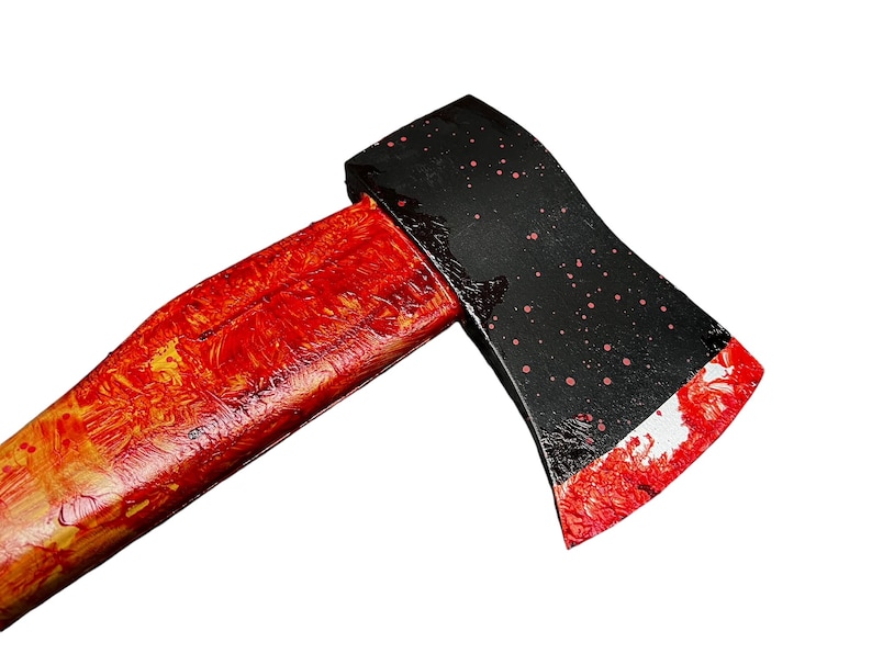K&ouml;nnte beinhalten: Eine schwarze Axt mit einem rot lackierten Holzstiel. Der Axtkopf hat rote Spritzer.
