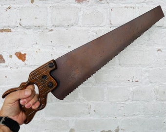 Könnte beinhalten: Eine vintage-Hand-Säge mit einem braunen Holzgriff und einer rostigen Metallklinge.