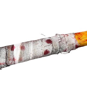 K&ouml;nnte beinhalten: Ein Holzstock, der in einen wei&szlig;en Verband mit roten Blutflecken gewickelt ist.