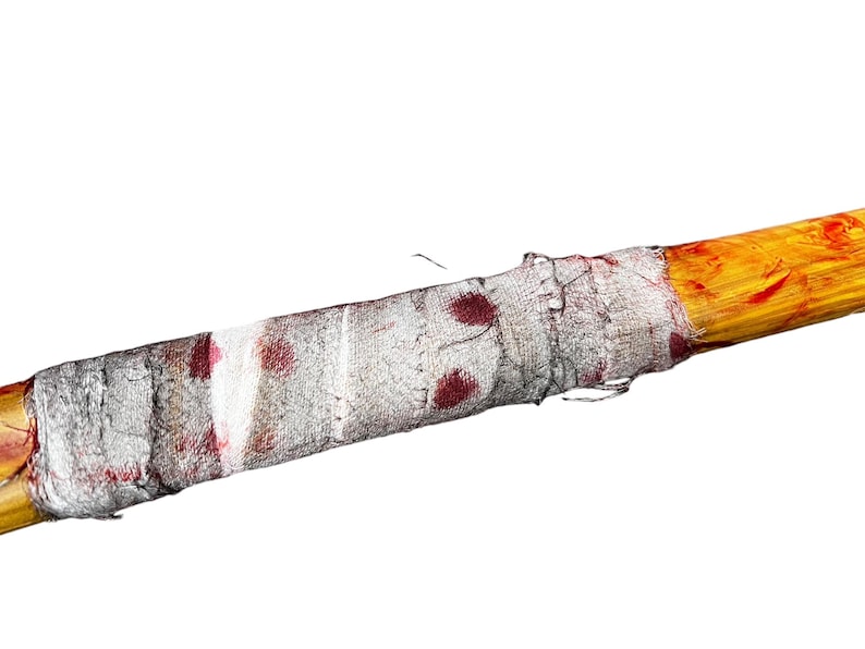 K&ouml;nnte beinhalten: Ein Holzstock, der in einen wei&szlig;en Verband mit roten Blutflecken gewickelt ist.