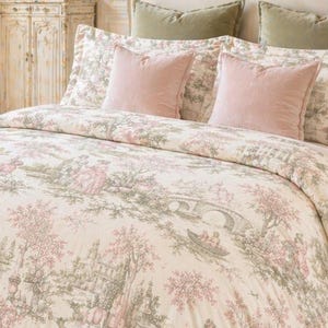 Op de afbeelding: Een bed met een crèmekleurig dekbed en bijpassende kussenslopen, met een roze en groene pastorale scène. Het bed is versierd met roze en groene kussens, geplaatst in een luxe slaapkamer met een kroonluchter en sierlijke meubels.