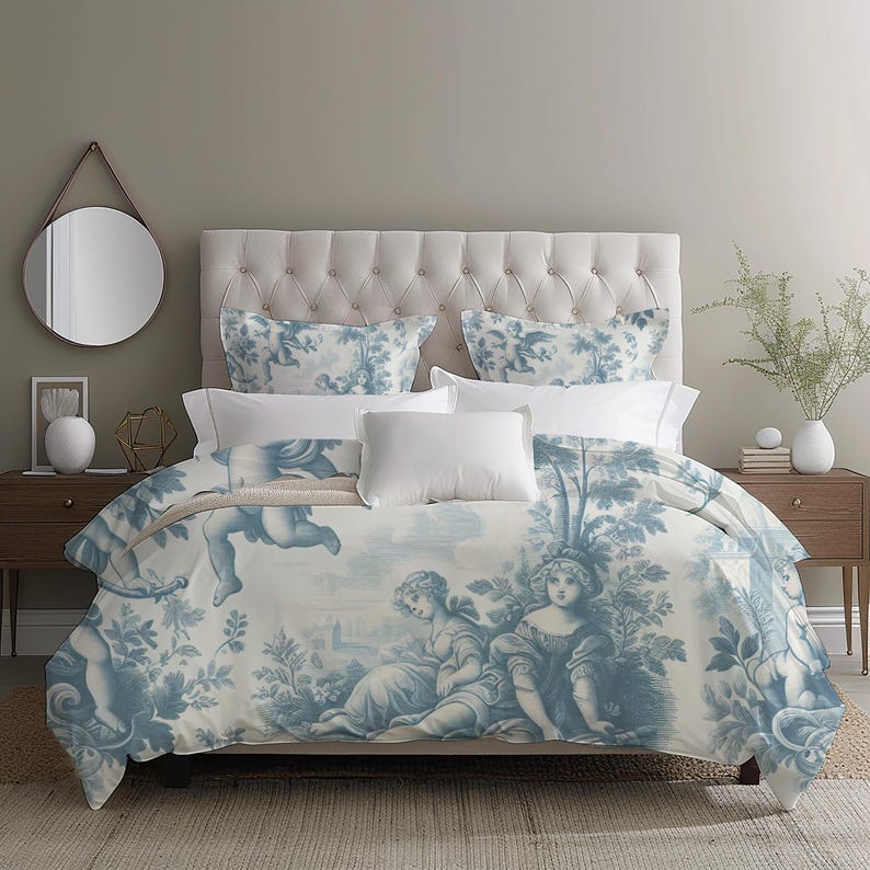 Puede incluir: Una cama con cabecero blanco acolchado y ropa de cama con estampado toile de Jouy azul y blanco. El estampado representa figuras y paisajes cl&aacute;sicos. Almohadas blancas y una colcha blanca completan el look. La habitaci&oacute;n tiene una paleta de colores neutros.