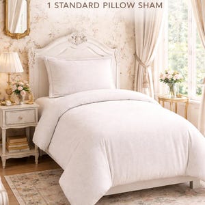 Puede incluir: Un juego de cama individual con edred&oacute;n y funda de almohada blancos. La ropa de cama est&aacute; sobre una estructura de cama blanca, con una alfombra con estampado floral debajo. El texto "TWIN SET" se muestra encima de la cama.