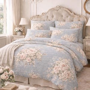 May include: A bed dressed with a light blue floral duvet cover and matching pillows, adorned with large pink roses and script writing. The text "Dusty Blue Script Romance" is visible at the bottom of the image.