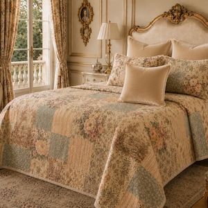 May include: A bed with a floral patterned quilt and pillows. The quilt features a patchwork design with beige, blue, and pink floral patterns. The headboard is ornate with a gold finish. The room has a classic, elegant style.
