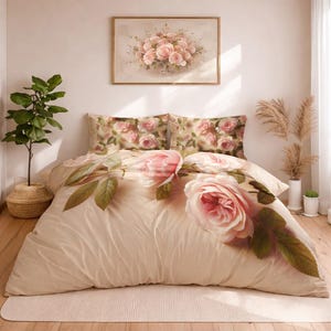 May include: A beige floral bedding set with large pink roses and green leaves. The set includes a duvet cover and two pillowcases. A framed floral painting hangs above the bed, complementing the bedding's design. The room has a neutral colour palette.
