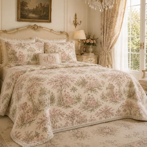 Könnte beinhalten: Eine cremefarbene Tagesdecke mit passenden Kissenbezügen, die ein wiederkehrendes Toile-Muster in gedeckten Rosa- und Grüntönen mit Figuren in einer Gartenlandschaft zeigt. Das Set enthält ein kleines rechteckiges Zierkissen mit Stickerei.