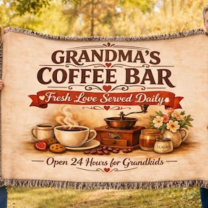 Könnte beinhalten: Eine beige Decke mit den Worten "Grandma's Coffee Bar" in brauner Schrift. Die Decke zeigt ein Kaffee-Thema-Design mit einer Kaffeemühle, Tassen und dem Text "Fresh Love Served Daily" und "Open 24 Hours for Grandkids."