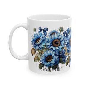 May include: White ceramic mug with a blue watercolor design of sunflowers with blue ribbons.