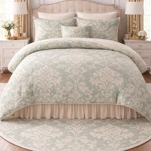 May include: A bedroom set with a bed featuring a light green and white floral patterned duvet cover, pillows, and a valance. A matching round rug is on the floor. The room has white bedside tables, lamps, and curtains.