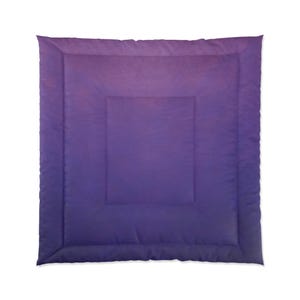 May include: A square comforter with a gradient design, transitioning from a deep purple at the edges to a lighter purple in the center. The comforter has a quilted pattern and a soft, inviting appearance.