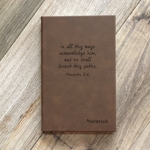 May include: A brown leather journal with the inscription "In all thy ways acknowledge him, and he shall direct thy paths. Proverbs 3:6" and the name "Maverick" on the bottom.
