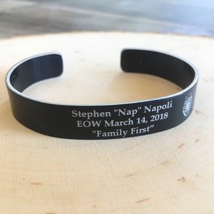 May include: Black metal bracelet with an engraved inscription: "Stephen "Nap" Napoli EOW March 14, 2018 "Family First"